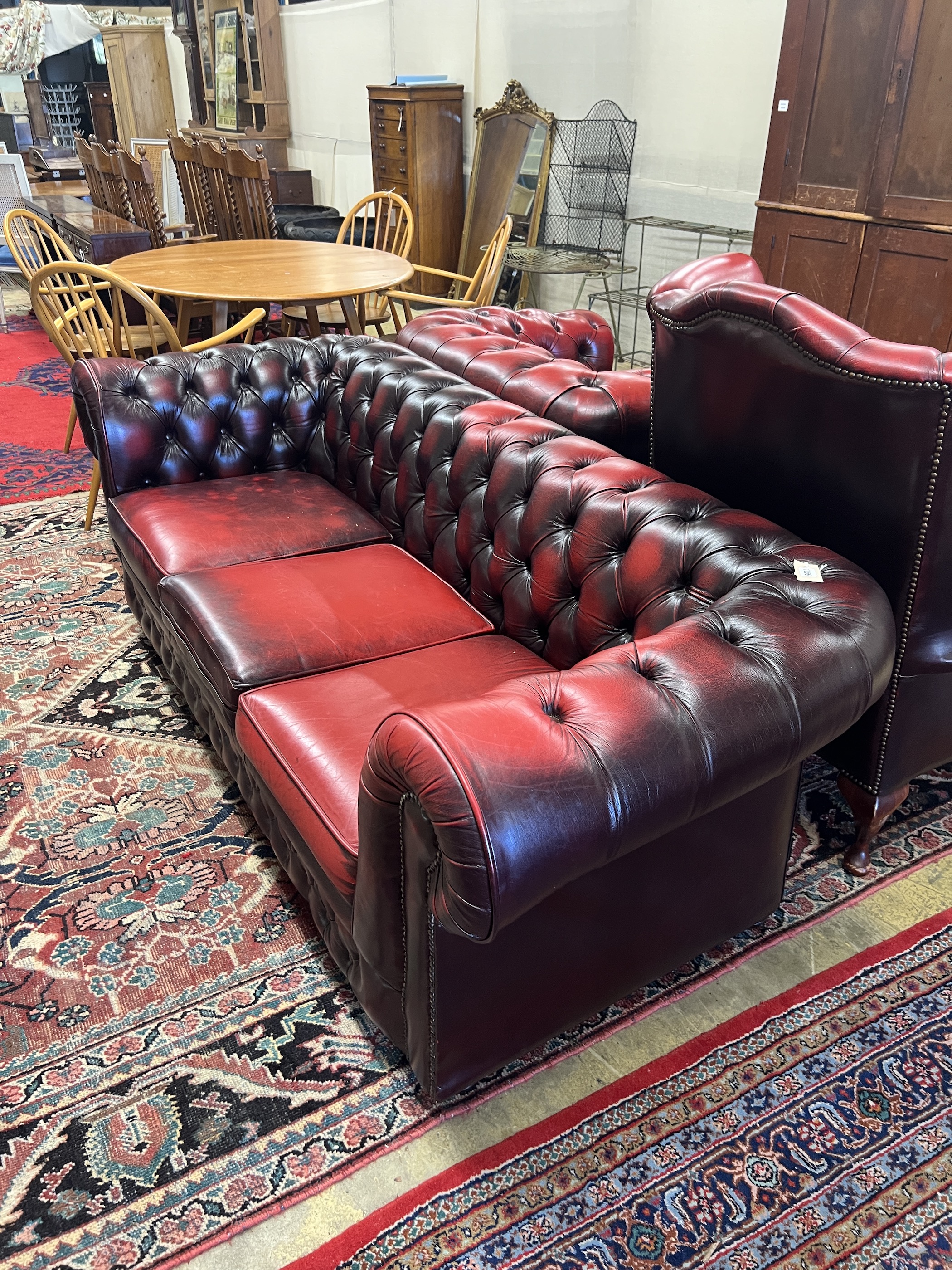 A Thomas Lloyd buttoned burgundy leather Chesterfield sofa, length 200cm, depth 85cm, height 72cm, two leather armchairs and a footstool